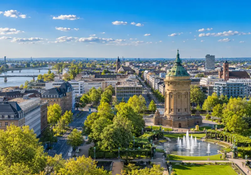 KI-Symbolbild: Blick über Mannheim mit Wasserturm und grüner Stadtsilhouette